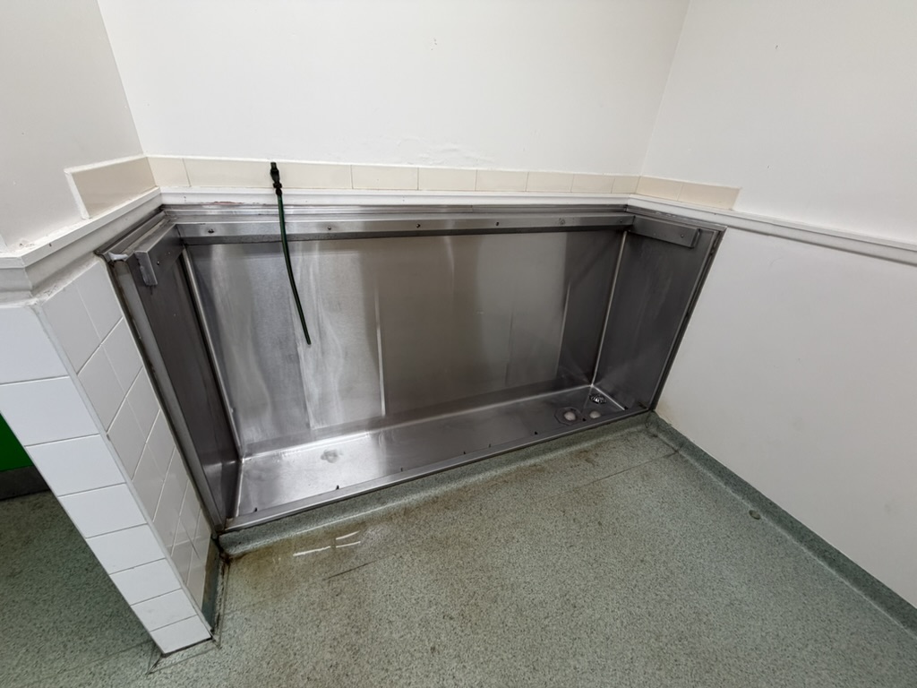 Degraded urinal trough with floor staining